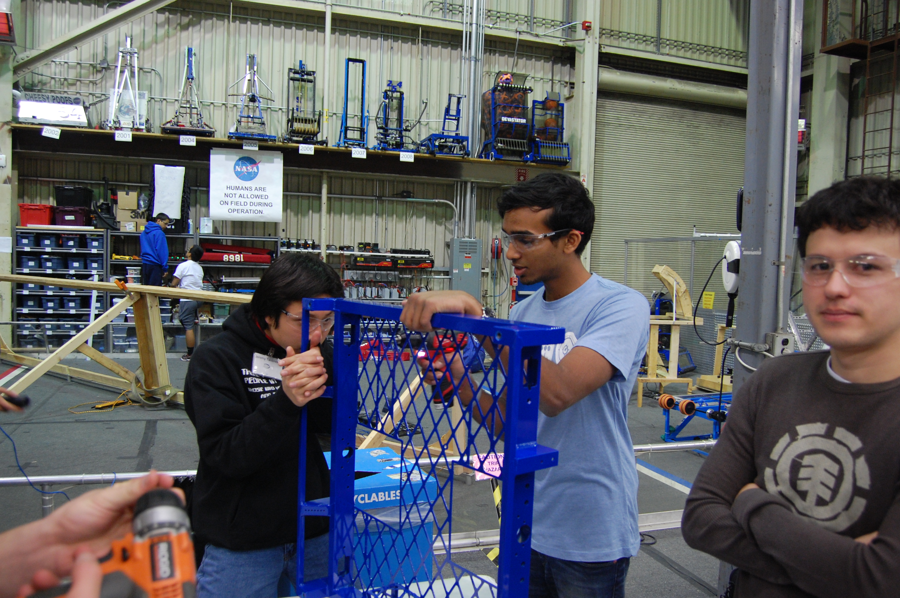 Abhi leading a group of students in drilling holes for the electronics